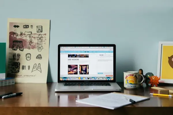 Laptop showing an early Mailchimp homepage on a desk with sketches and a mug