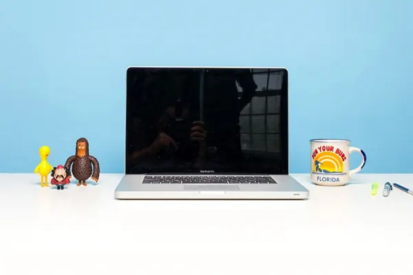 Laptop and Freddie figure on a white table against a blue wall