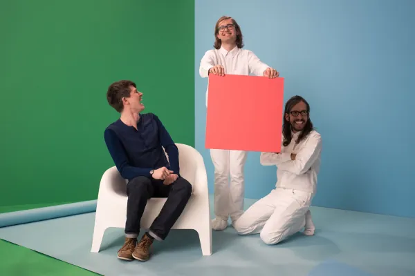 Studio set with two people holding a pink square on blue and green walls